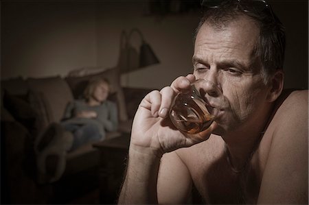 simsearch:6102-05802624,k - Mature man drinking, woman on sofa on background Stock Photo - Premium Royalty-Free, Code: 6102-07768705