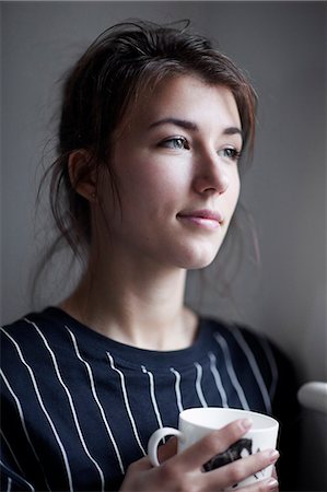 Portrait of young woman with mug, studio shot Stock Photo - Premium Royalty-Free, Code: 6102-07768844