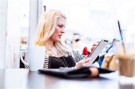 simsearch:6102-08881660,k - Young woman in cafe using digital tablet Photographie de stock - Premium Libres de Droits, Code: 6102-07769240