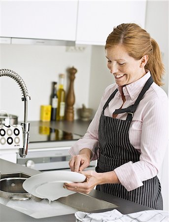 simsearch:6102-08120280,k - Smiling woman washing dishes Photographie de stock - Premium Libres de Droits, Code: 6102-07842892