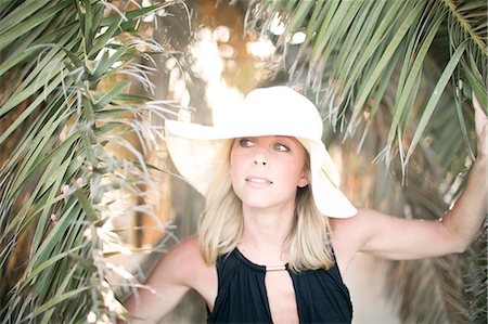 simsearch:6102-07789651,k - Mid adult woman wearing sun hat near palm tree Stock Photo - Premium Royalty-Free, Code: 6102-07843002