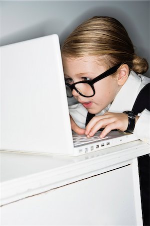 Girl dressed as businesswoman using laptop, studio shot Stock Photo - Premium Royalty-Free, Code: 6102-07843160