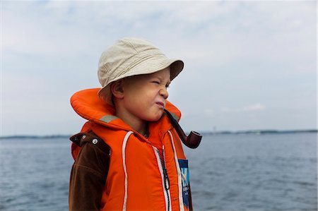 Boy wearing life vest with smoking pipe Stock Photo - Premium Royalty-Free, Code: 6102-07843345