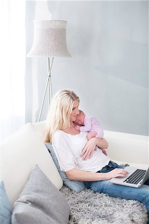 simsearch:6102-07843029,k - Woman holding newborn daughter and using laptop Photographie de stock - Premium Libres de Droits, Code: 6102-07843436