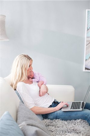 simsearch:6102-07843029,k - Woman holding newborn daughter and using laptop Photographie de stock - Premium Libres de Droits, Code: 6102-07843439