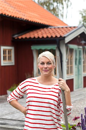simsearch:6102-03750096,k - Smiling woman standing in front of house Stock Photo - Premium Royalty-Free, Code: 6102-07843592