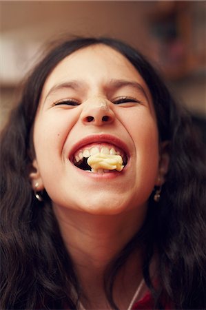 Portrait of smiling girl with cookie in her mouth Photographie de stock - Premium Libres de Droits, Code: 6102-07843788