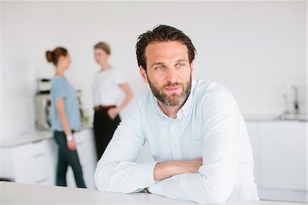 simsearch:6102-07769345,k - Mid adult man in office, people on background Stock Photo - Premium Royalty-Free, Code: 6102-07843714