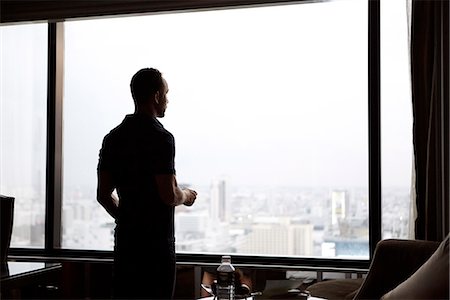 Man looking through window at cityscape Foto de stock - Sin royalties Premium, Código: 6102-07844039