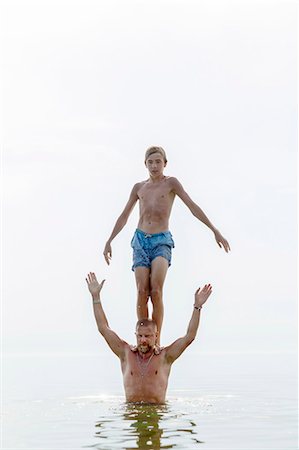 father teenage son not illustration not monochrome and two people not illustration not monochrome - Teenager standing on fathers shoulders in water Stock Photo - Premium Royalty-Free, Code: 6102-08000931