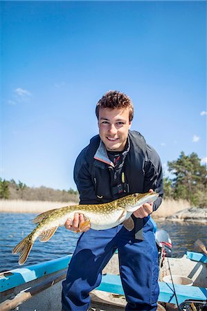 Young man holding caught fish Photographie de stock - Premium Libres de Droits, Code: 6102-08001379