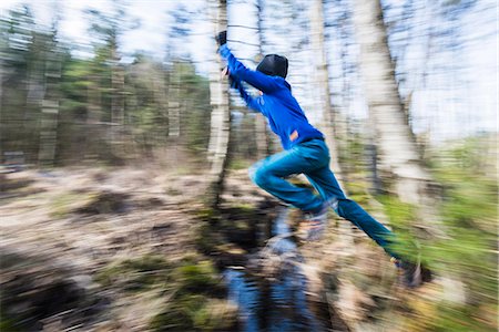 Boy jumping through stream Stock Photo - Premium Royalty-Free, Code: 6102-08168669