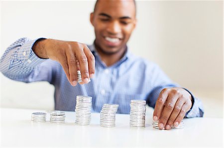 simsearch:6102-08168957,k - Young man putting coin in piggybank Stock Photo - Premium Royalty-Free, Code: 6102-08168956