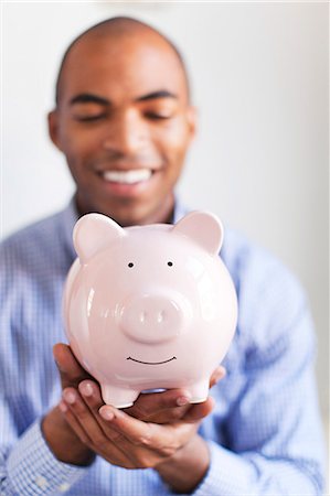 simsearch:6102-08168957,k - Young man holding piggybank Stock Photo - Premium Royalty-Free, Code: 6102-08168960