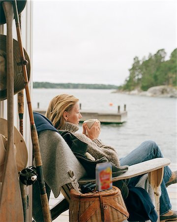 Woman looking at water with hot drink Stock Photo - Premium Royalty-Free, Code: 6102-08120883