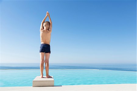 Boy standing on edge of swimming-pool Stock Photo - Premium Royalty-Free, Code: 6102-08270758