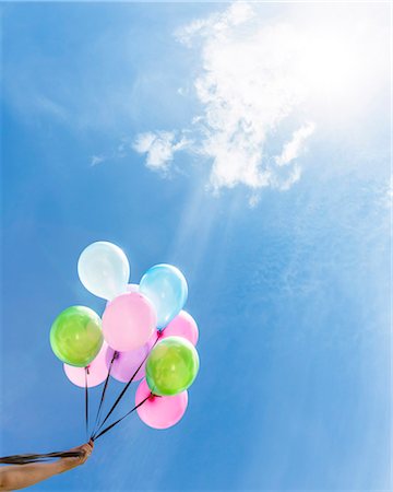 précaution - Hand holding balloons against blue sky Photographie de stock - Premium Libres de Droits, Code: 6102-08270844
