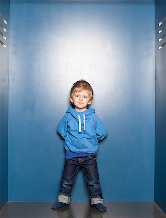 Boy standing against blue wall Foto de stock - Sin royalties Premium, Código: 6102-08271031