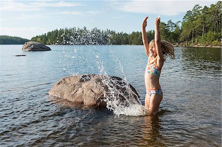 Happy girl splashing water in lake Photographie de stock - Premium Libres de Droits, Code: 6102-08271457