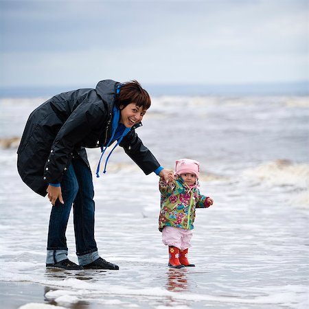 simsearch:6102-08270740,k - Mother with daughter standing on beach Fotografie stock - Premium Royalty-Free, Codice: 6102-08271472