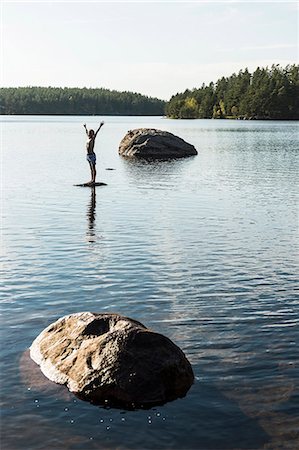 simsearch:6102-08760609,k - Boy standing on rock in lake Photographie de stock - Premium Libres de Droits, Code: 6102-08271435