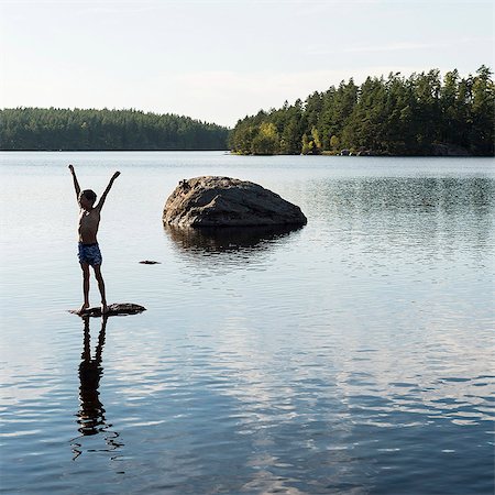 simsearch:6102-08120534,k - Boy standing on rock in lake Photographie de stock - Premium Libres de Droits, Code: 6102-08271436