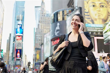 Smiling woman on city street talking via cell phone Stock Photo - Premium Royalty-Free, Code: 6102-08271717