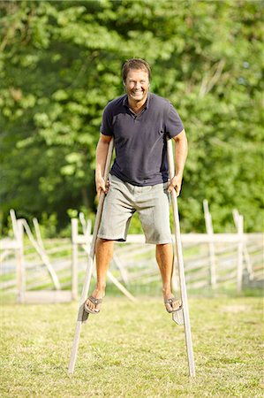 Smiling man walking on stilts Stock Photo - Premium Royalty-Free, Code: 6102-08271823