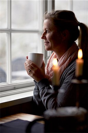 simsearch:6102-08683485,k - Woman having coffee and looking through window Stock Photo - Premium Royalty-Free, Code: 6102-08278853