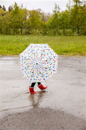 rainy day crossing - Child with umbrella walking through puddle Stock Photo - Premium Royalty-Free, Code: 6102-08384416