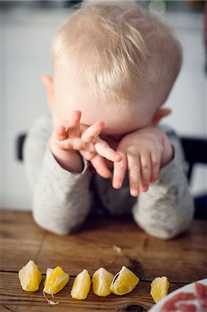 Small boy sitting at table and hiding face with hands Stock Photo - Premium Royalty-Free, Code: 6102-08384584