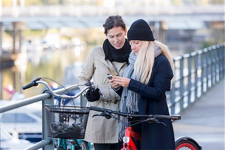 simsearch:6102-08388194,k - Women with bicycles looking at cell phone Foto de stock - Royalty Free Premium, Número: 6102-08388193