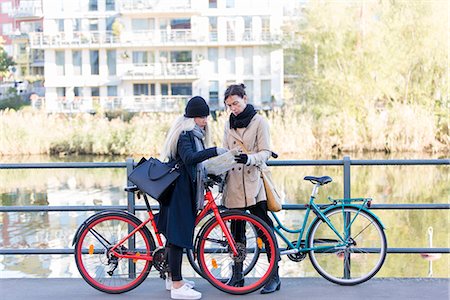 simsearch:6102-08388194,k - Women with bicycles looking at map Foto de stock - Royalty Free Premium, Número: 6102-08388191