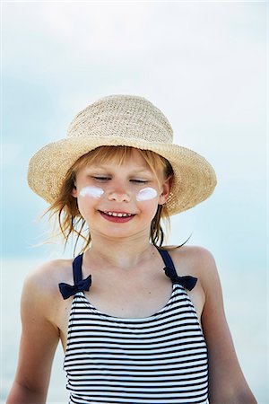 Smiling girl in swimsuit with suntan cream on face Photographie de stock - Premium Libres de Droits, Code: 6102-08388295