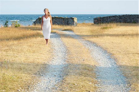 simsearch:6102-08278885,k - Woman walking on dirt track at sea Stock Photo - Premium Royalty-Free, Code: 6102-08329651