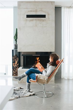 simsearch:6102-08120116,k - Woman reading book in front of fireplace Stock Photo - Premium Royalty-Free, Code: 6102-08329977