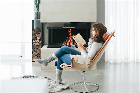 sessel - Woman reading book in front of fireplace Stockbilder - Premium RF Lizenzfrei, Bildnummer: 6102-08329980