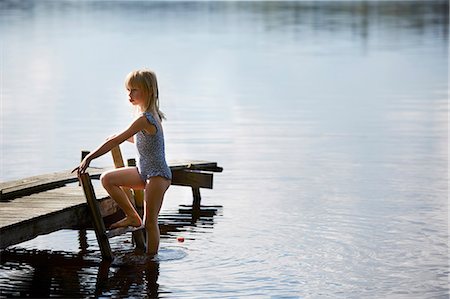 Girl standing on jetty with fishing net - Stock Photo - Masterfile