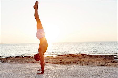 Man doing handstand on beach at sunset Stock Photo - Premium Royalty-Free, Code: 6102-08481320