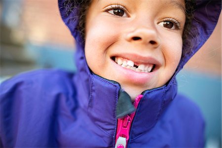 raincoat hood - Smiling girl with missing tooth Stock Photo - Premium Royalty-Free, Code: 6102-08481491