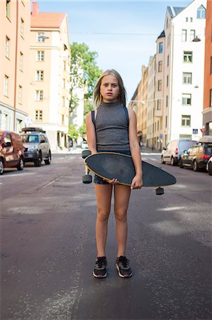 Girl standing in street, holding skateboard Stock Photo - Premium Royalty-Free, Code: 6102-08481507
