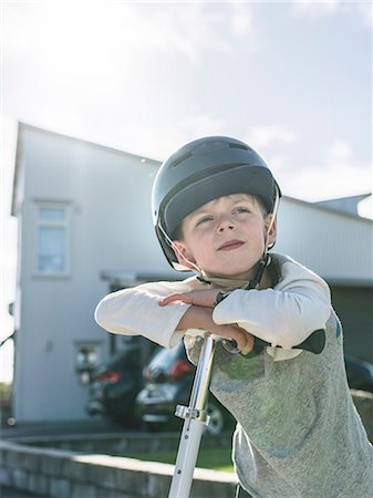 Boy in bicycle helmet standing with kick scooter Stock Photo - Premium Royalty-Free, Code: 6102-08542227