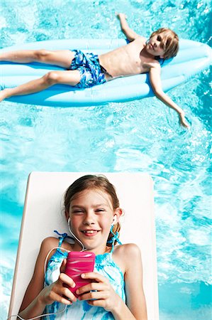 Boy and girl with mp3 player on pool rafts Stock Photo - Premium Royalty-Free, Code: 6102-08558891