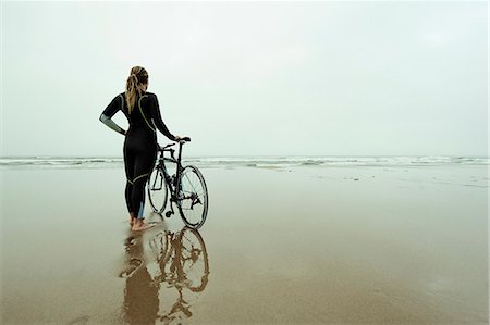 Young woman wearing wetsuit and standing with bike on beach Photographie de stock - Premium Libres de Droits, Code: 6102-08558967