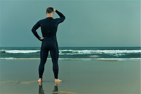 simsearch:6102-07768988,k - Man wearing wetsuit and standing on beach Stock Photo - Premium Royalty-Free, Code: 6102-08558979