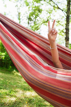 Girl resting in hammock and showing peace sign Stock Photo - Premium Royalty-Free, Code: 6102-08566129