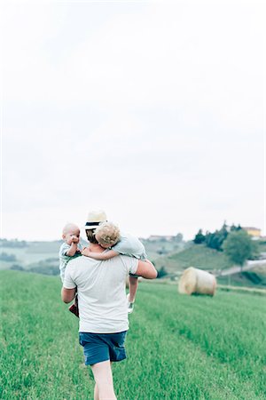 simsearch:6102-08761638,k - Father carrying children through field Foto de stock - Royalty Free Premium, Número: 6102-08566383