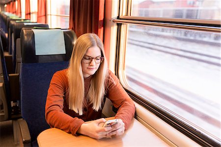 simsearch:6102-08942601,k - Young woman using cell phone in train Stock Photo - Premium Royalty-Free, Code: 6102-08566583