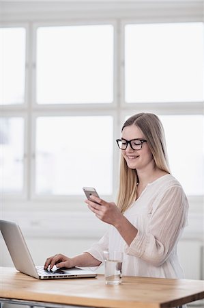 student working home office - Smiling woman using cell phone Stock Photo - Premium Royalty-Free, Code: 6102-08566662