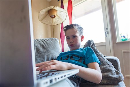 Boy using laptop on sofa Foto de stock - Sin royalties Premium, Código: 6102-08566699